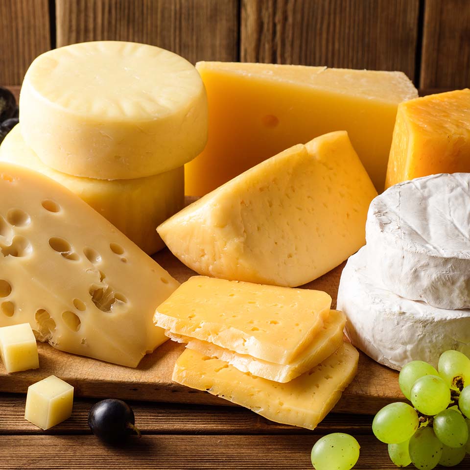 Various types of cheese on dark rustic wooden background. Selective focus.